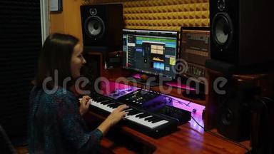 女子在电钢琴演奏和创作歌曲在专业录音室。 女音乐家会弹钢琴、键盘和键盘